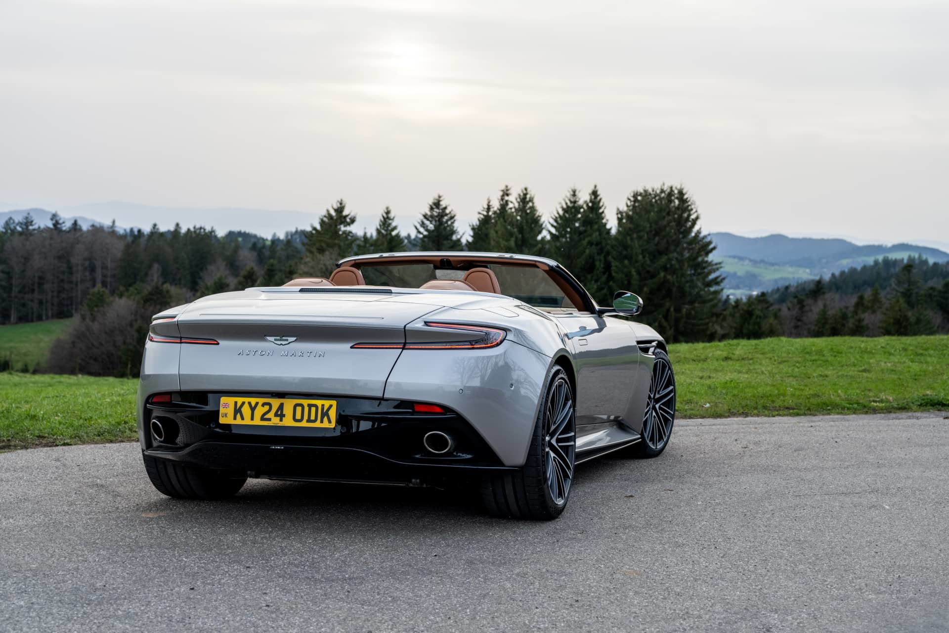 Vista trasera lateral del Aston Martin DB12 Volante, destacando su diseño aerodinámico y elegante.