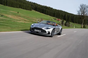 Vista dinámica del Aston Martin DB12 Volante en carretera. Elegancia y potencia británica en movimiento.