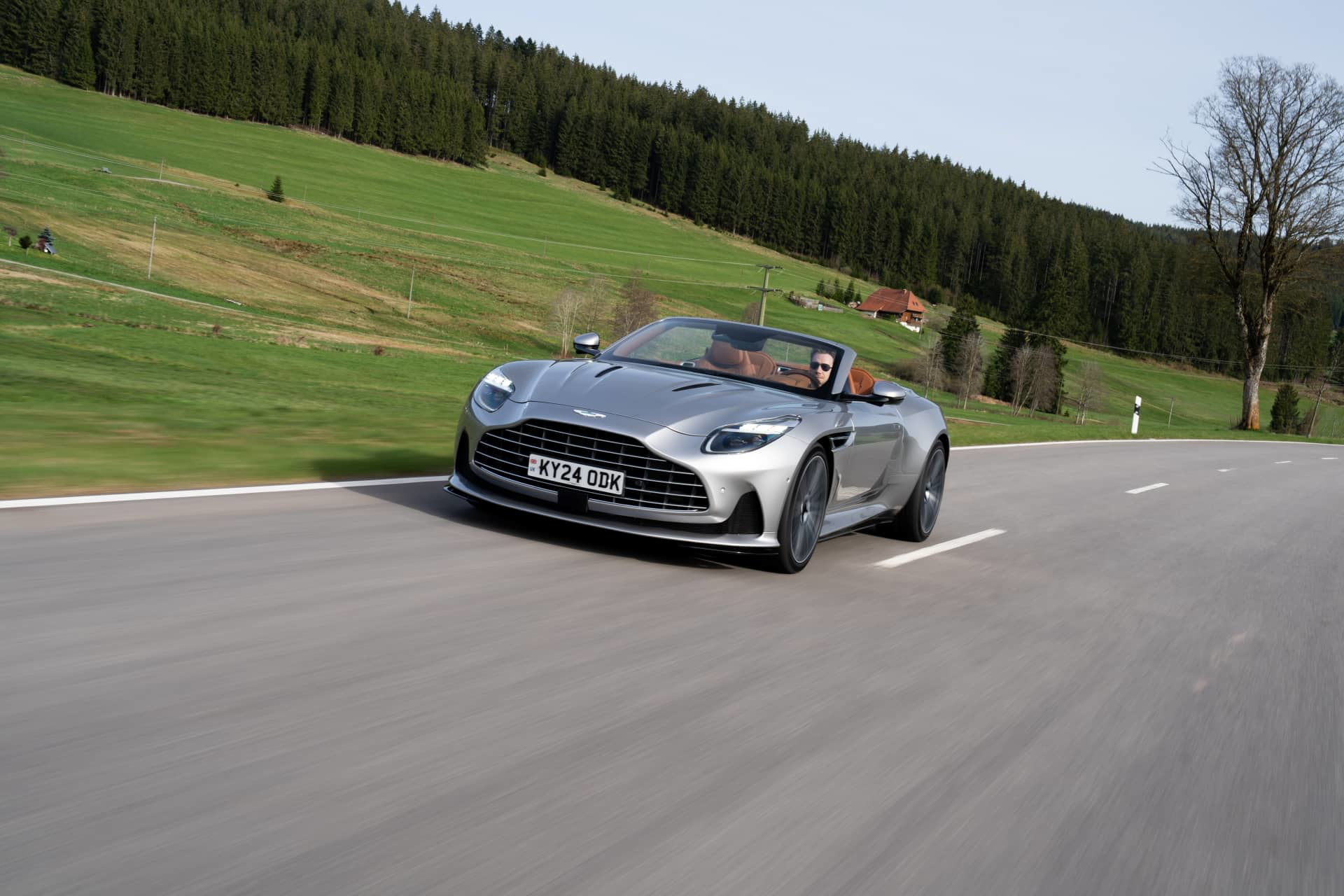 Vista dinámica del Aston Martin DB12 Volante en carretera. Elegancia y potencia británica en movimiento.