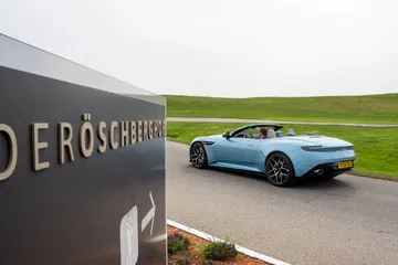 Vista lateral del Aston Martin DB12 Volante con capota bajada, mostrando su elegante línea.