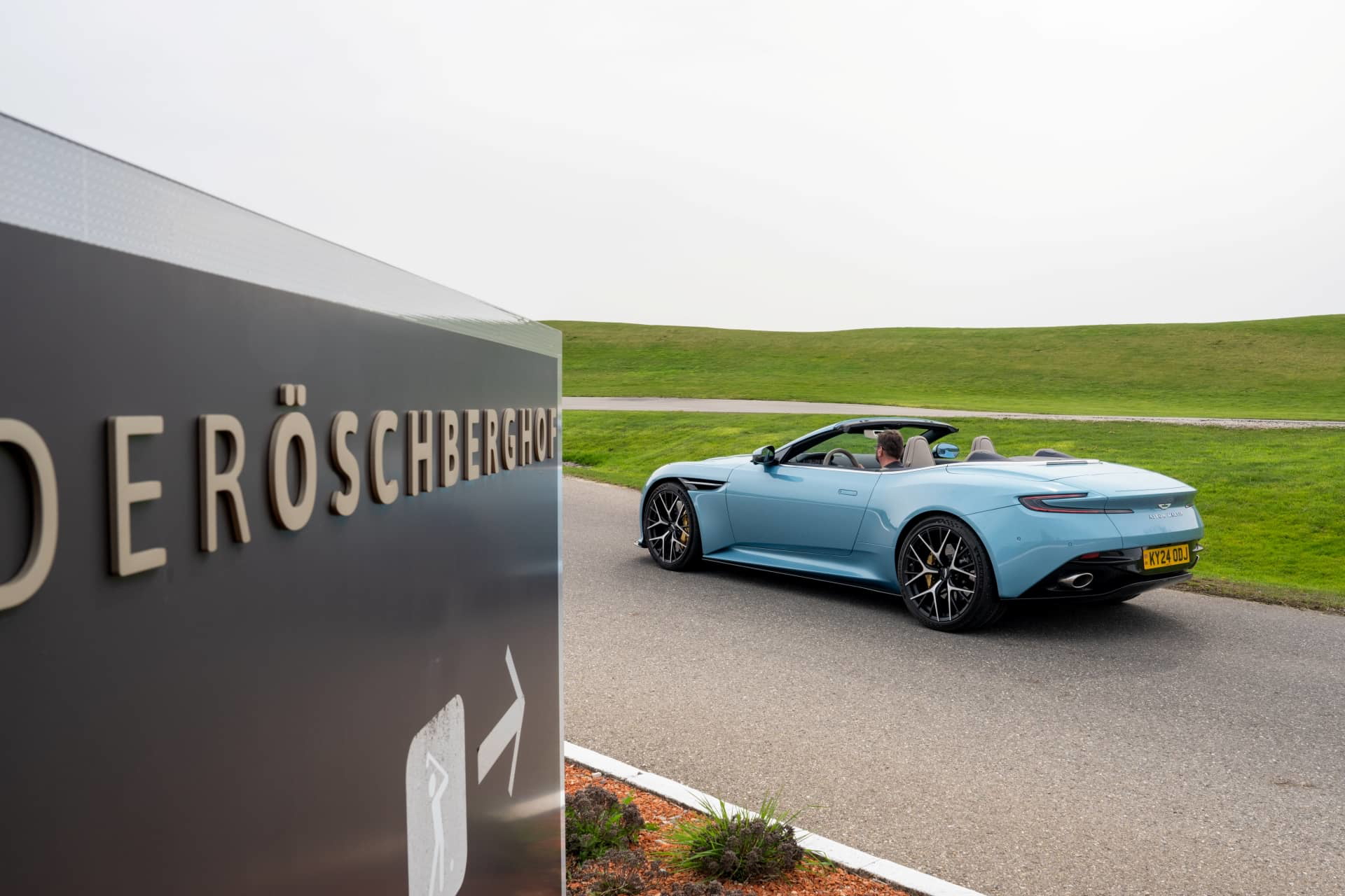 Vista lateral del Aston Martin DB12 Volante con capota bajada, mostrando su elegante línea.