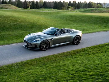 Vista lateral del Aston Martin DB12 Volante sobre césped con capota bajada.