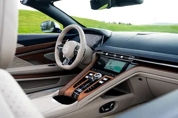 Vista lateral interior del Aston Martin DB12 Volante con acabados en madera y cuero.