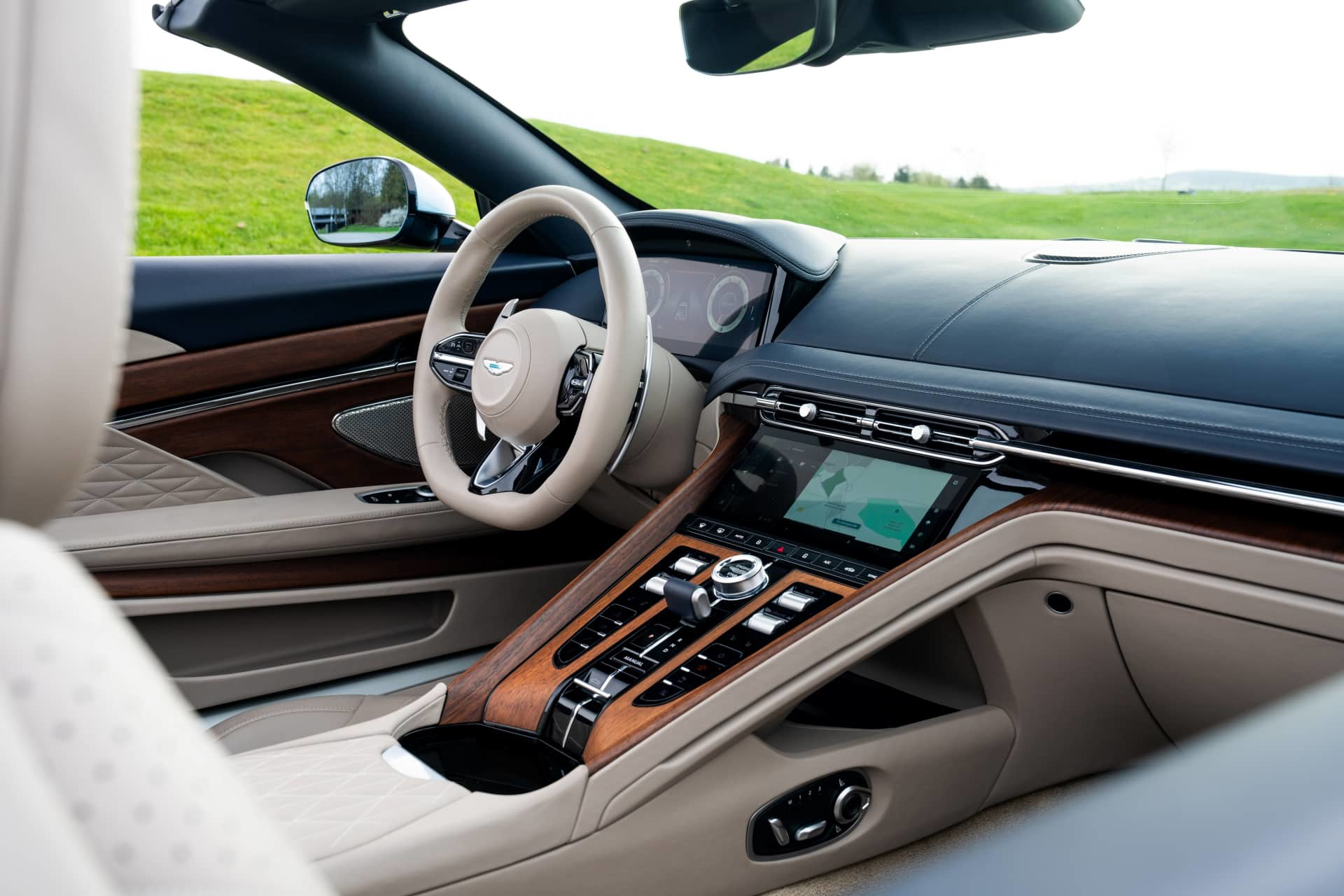 Vista lateral interior del Aston Martin DB12 Volante con acabados en madera y cuero.
