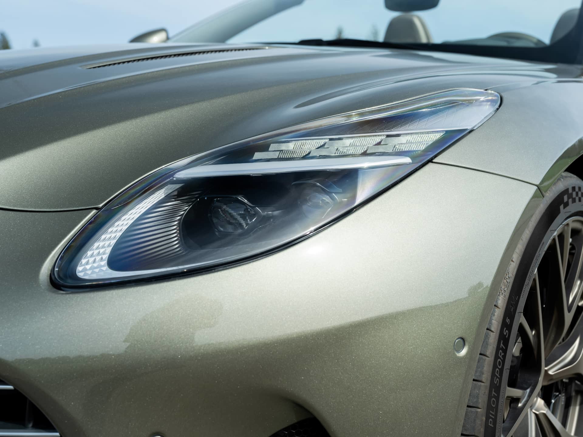 Exquisita toma del detalle del faro del Aston Martin DB12 Volante, precisión británica.
