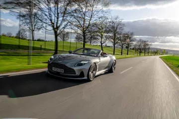 Aston Martin DB12 Volante en movimiento, majestuosa presencia y diseño deportivo.