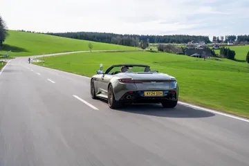 Vista dinámica del Aston Martin DB12 Volante 2024 deslizándose por carretera