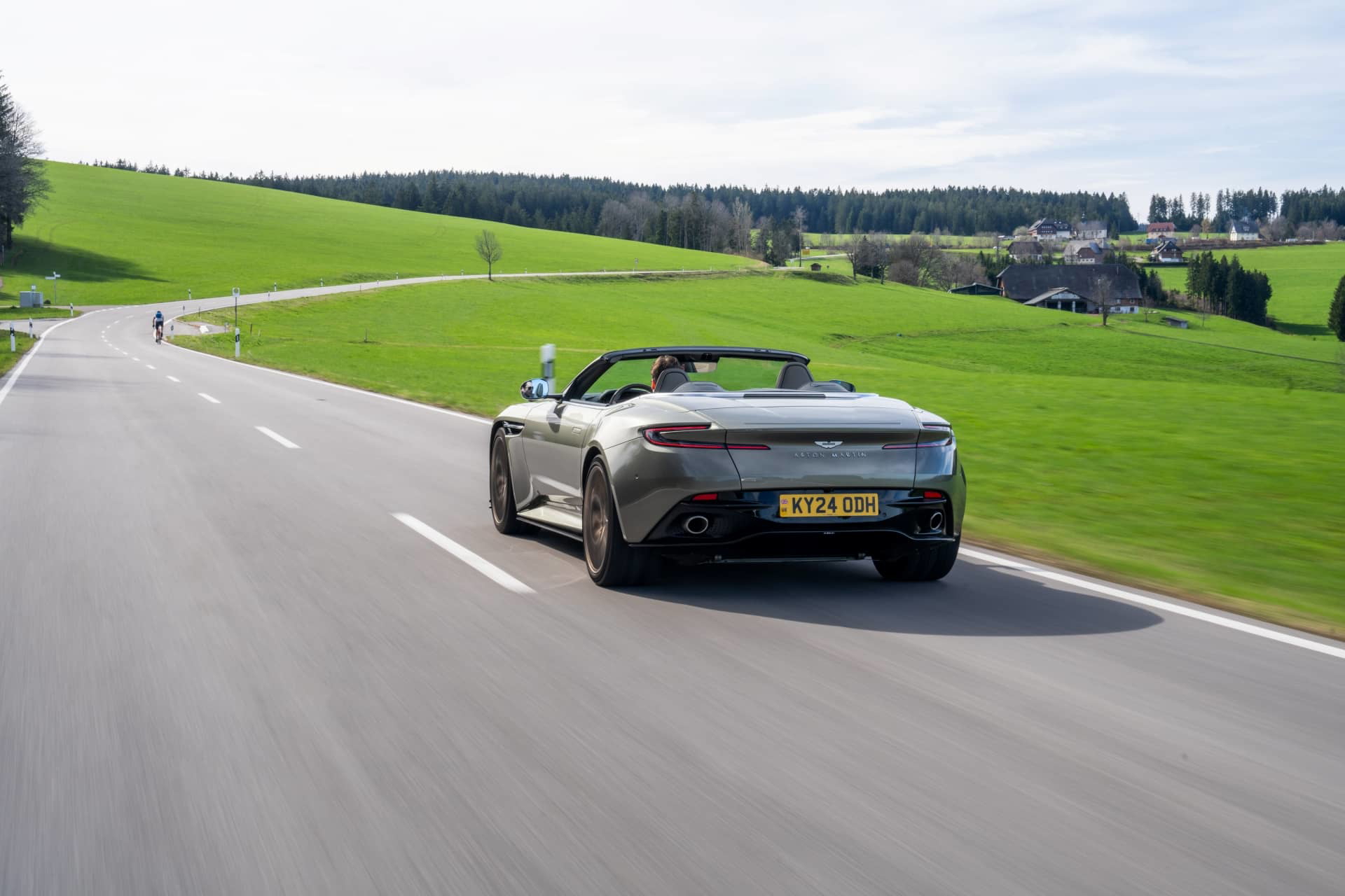 Vista dinámica del Aston Martin DB12 Volante 2024 deslizándose por carretera