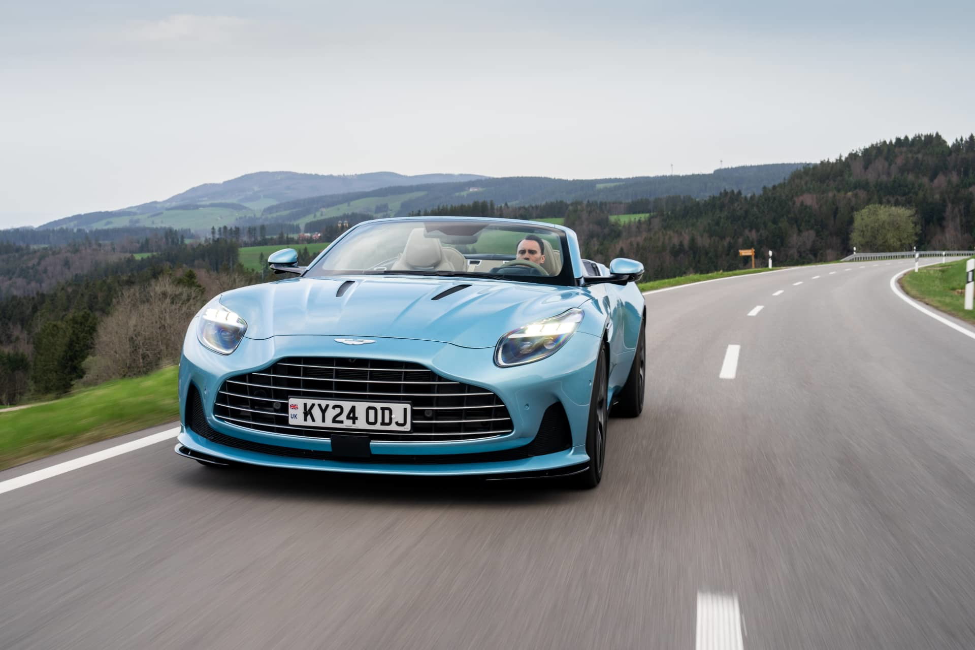 El Aston Martin DB12 Volante 2024 capturado en movimiento, mostrando su línea aerodinámica y frontal elegante.