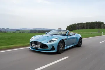 Vista dinámica del Aston Martin DB12 Volante, mostrando su agresiva estampa en movimiento.