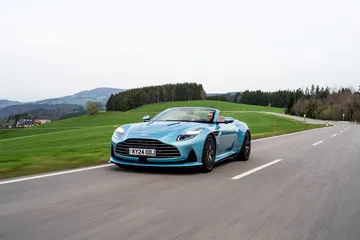 Vista dinámica del Aston Martin DB12 Volante mostrando su perfil elegante y agresivo frontal.
