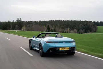 Vista dinámica del Aston Martin DB12 Volante en carretera, énfasis en diseño trasero