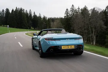 Aston Martin DB12 Volante capturado en pleno dinamismo, mostrando su elegante diseño trasero y lateral.