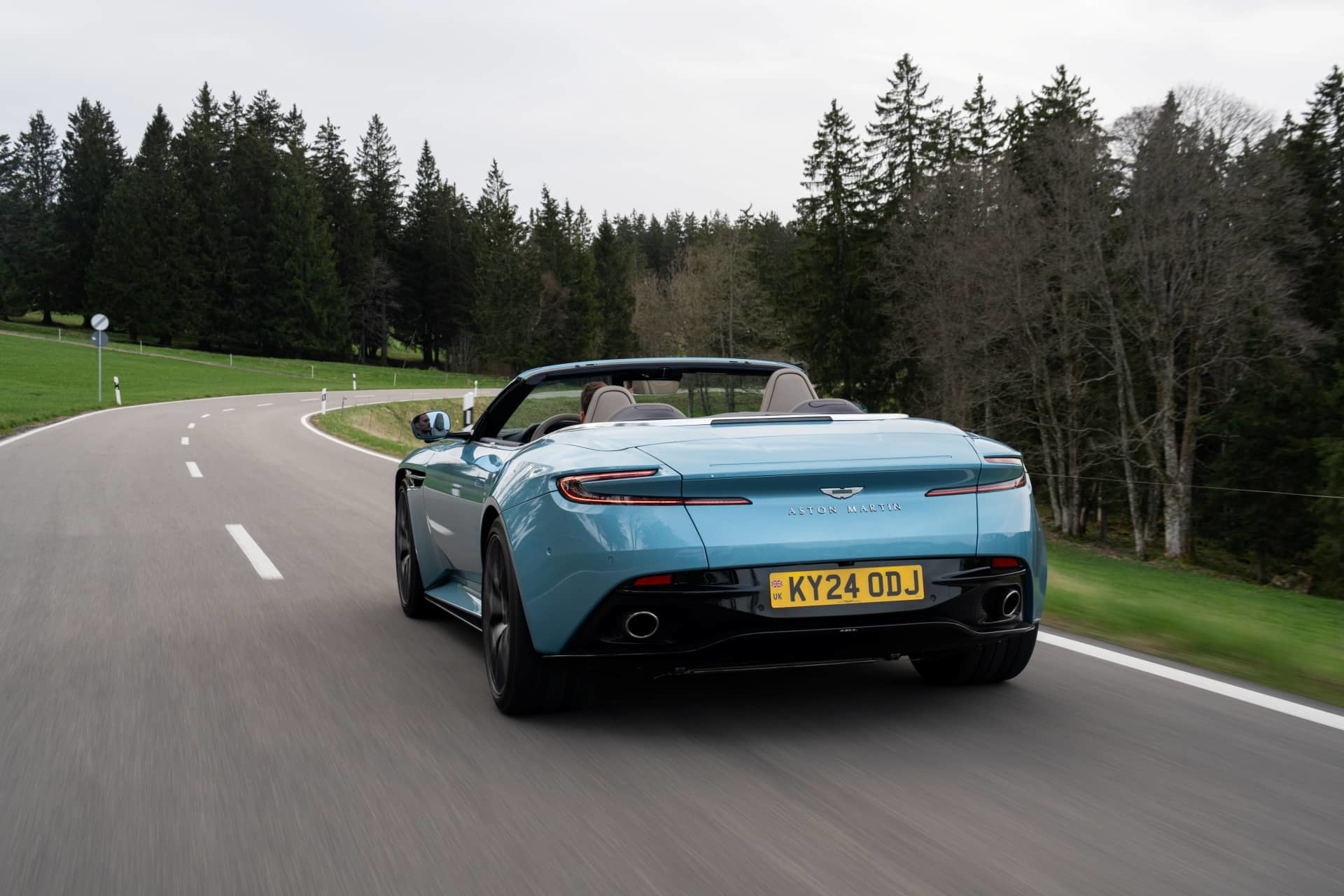 Aston Martin DB12 Volante capturado en pleno dinamismo, mostrando su elegante diseño trasero y lateral.