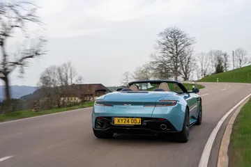 El nuevo Aston Martin DB12 Volante 2024 en acción, mostrando su diseño trasero y perfil lateral.
