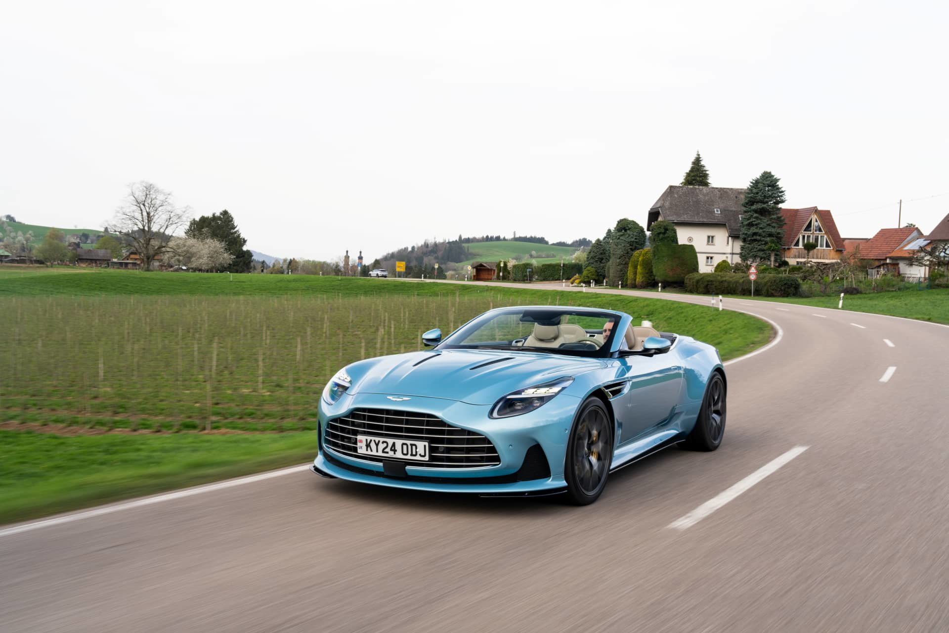 Vista dinámica del Aston Martin DB12 Volante, lujo y rendimiento británicos en movimiento.