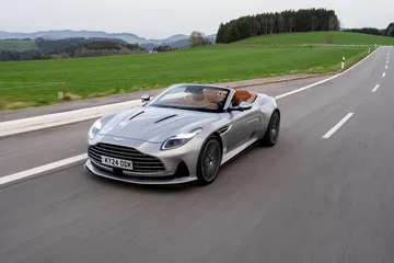 Aston Martin DB12 Volante en movimiento, capturado desde el frente y lado, diseño elegante.