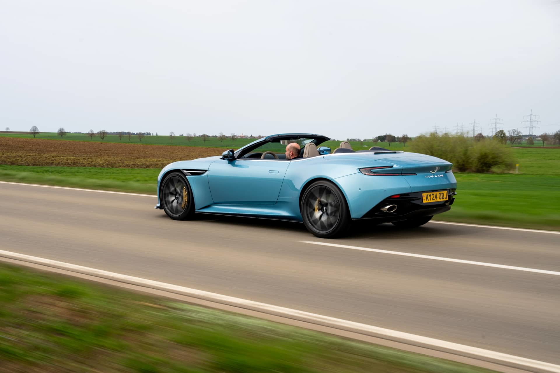Aston Martin DB12 Volante 2024 capturado en acción, perfil elegante y dinámico