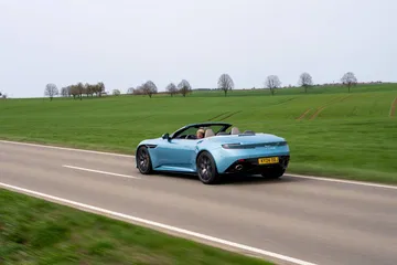 Vista en movimiento del Aston Martin DB12 Volante mostrando su elegancia y dinamismo.