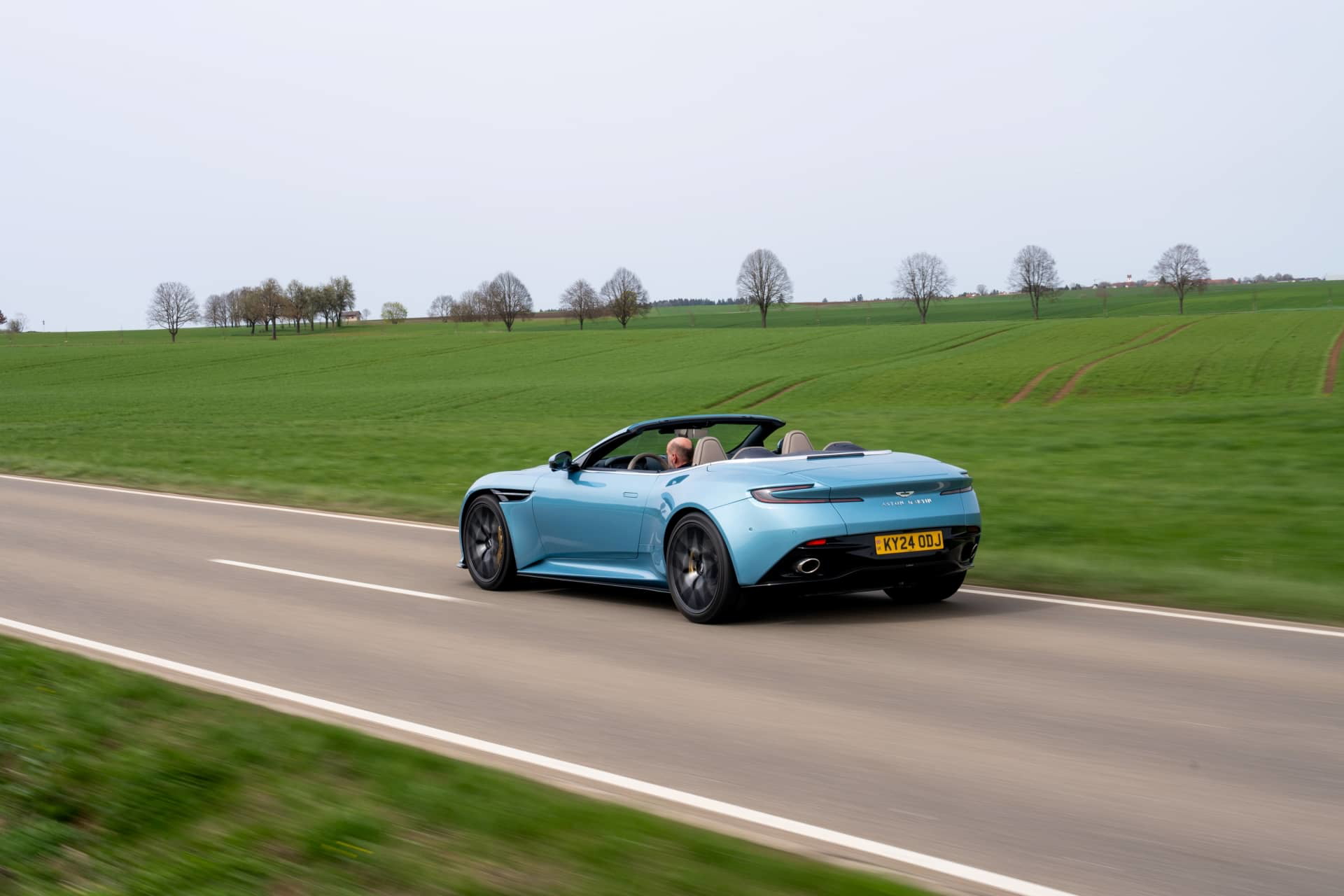 Vista en movimiento del Aston Martin DB12 Volante mostrando su elegancia y dinamismo.