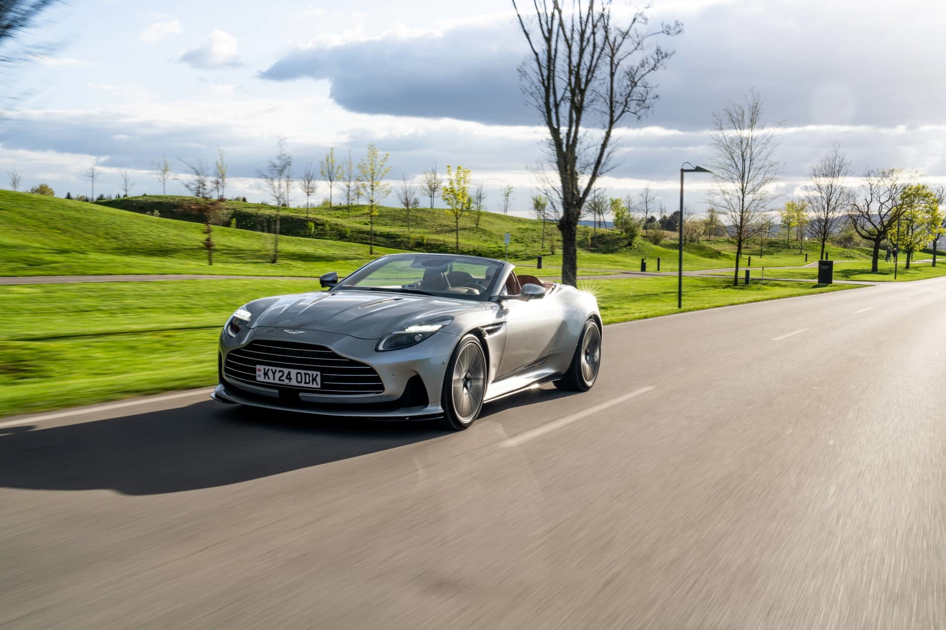 Aston Martin DB12 Volante en movimiento, mostrando su diseño lateral aerodinámico.
