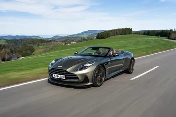 Aston Martin DB12 Volante en movimiento, muestra su perfil y diseño aerodinámico.