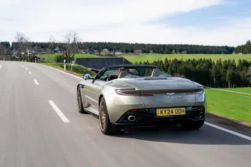 Vista dinámica del Aston Martin DB12 Volante mostrando su línea trasera y lateral.
