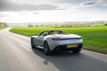 Vista dinámica del Aston Martin DB12 Volante en carretera, mostrando su elegante silueta.