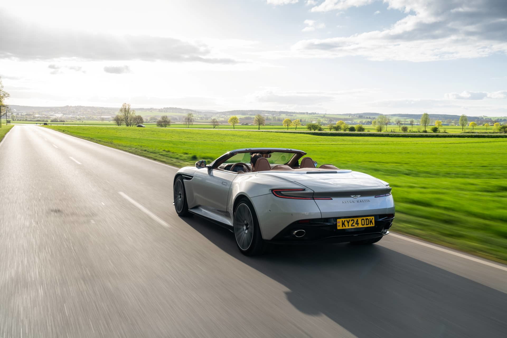 Vista trasera y lateral del Aston Martin DB12 Volante en movimiento.