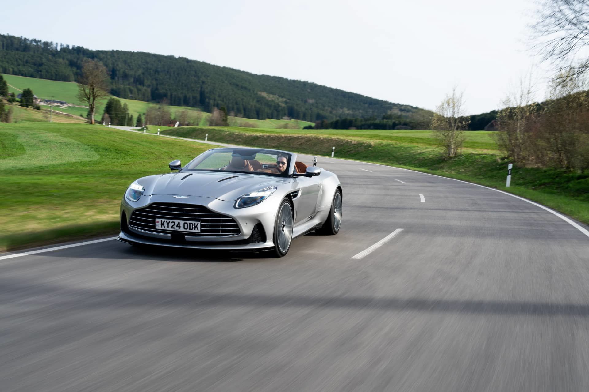 Elegante Aston Martin DB12 Volante captado en plena acción, mostrando su diseño lateral y silueta