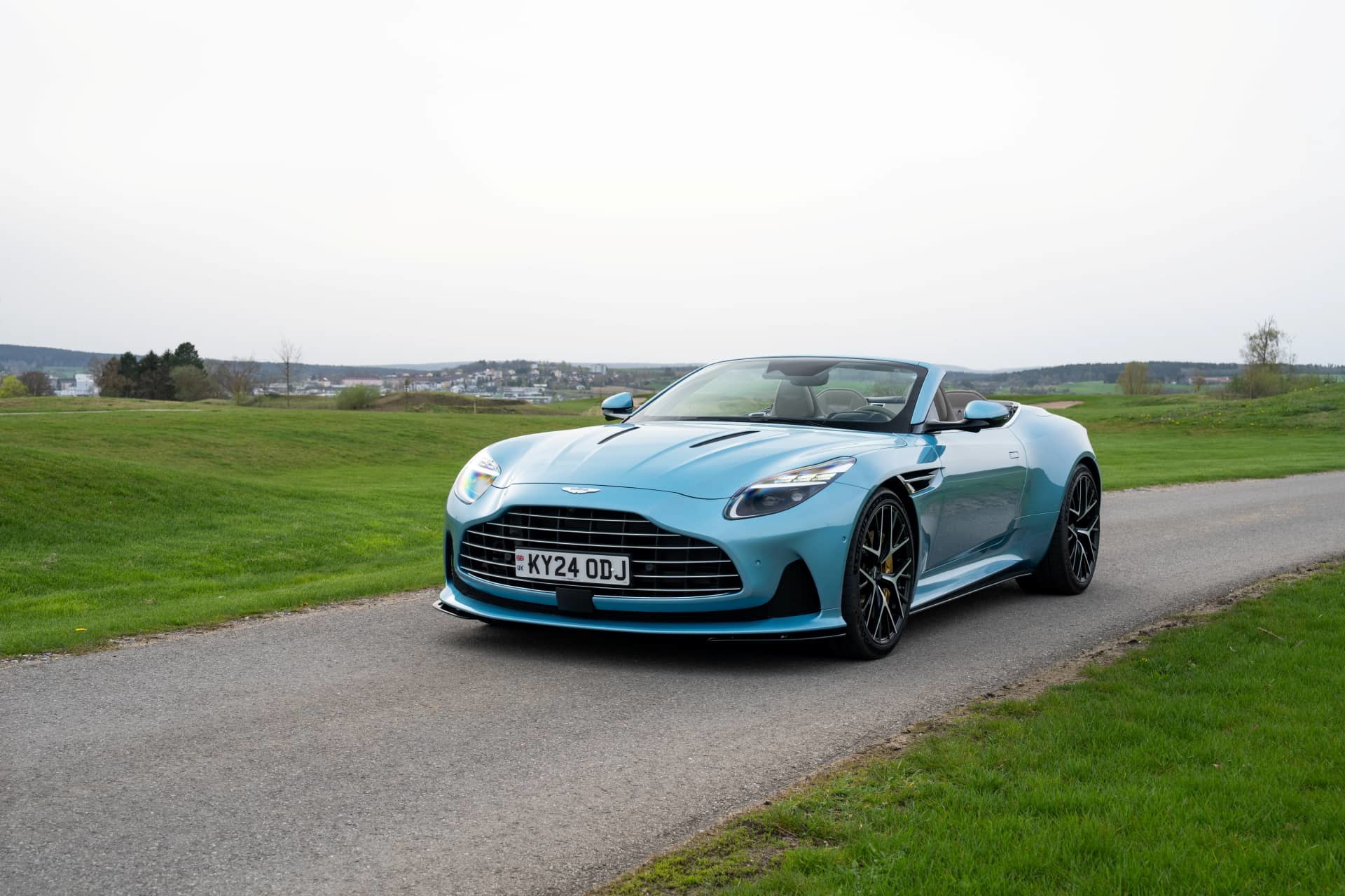 Vista delantera y lateral del Aston Martin DB12 Volante, mostrando su elegante diseño y características aerodinámicas.