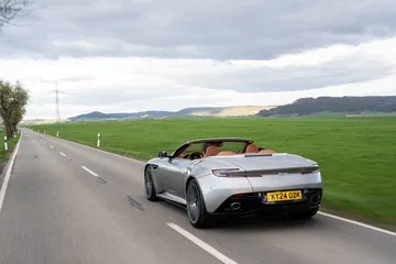 Vista dinámica del Aston Martin DB12 Volante mostrando su silueta y diseño trasero.