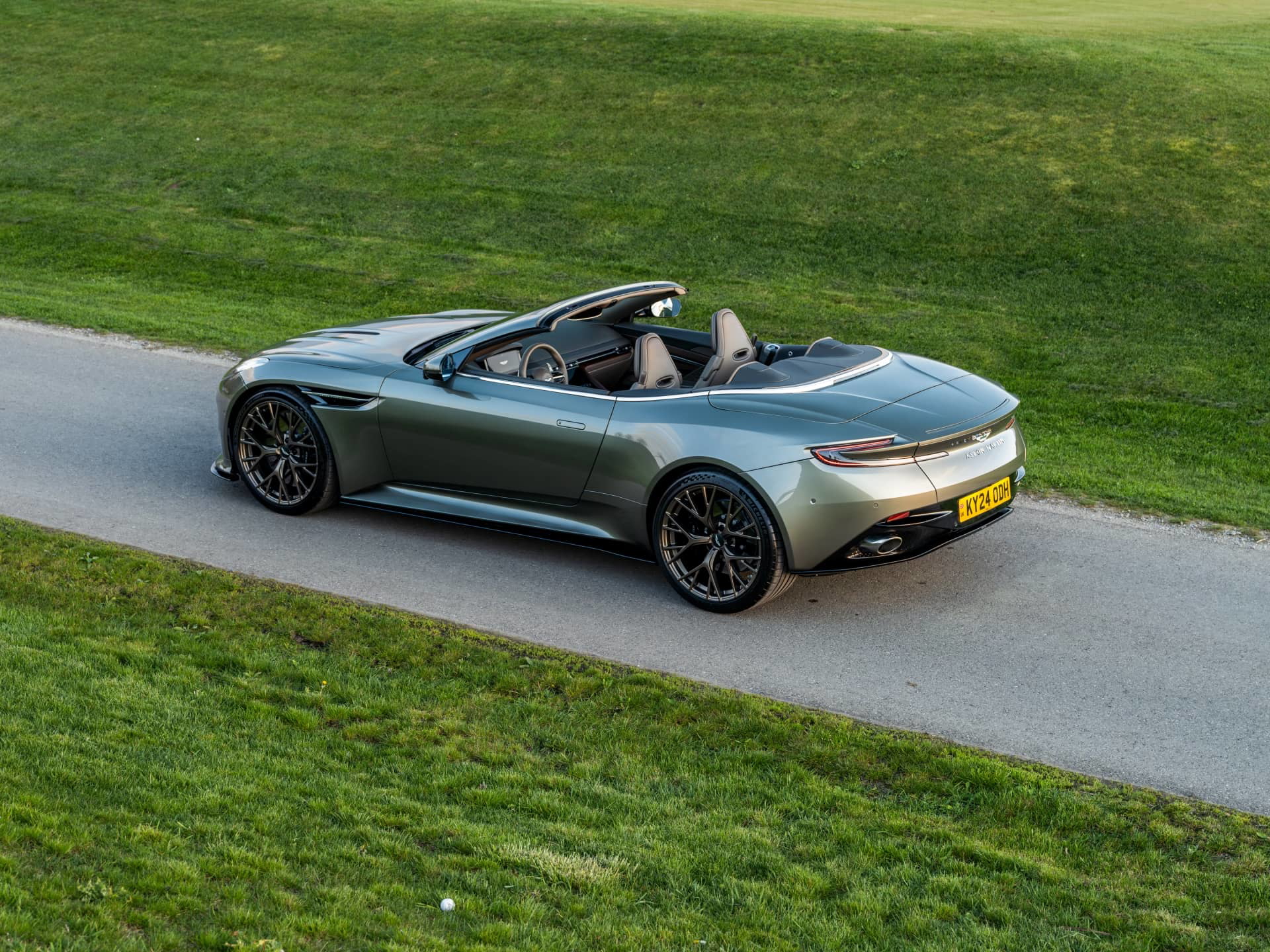 Aston Martin DB12 Volante captado en plena maniobra, el diseño lateral revela elegancia y deportividad.
