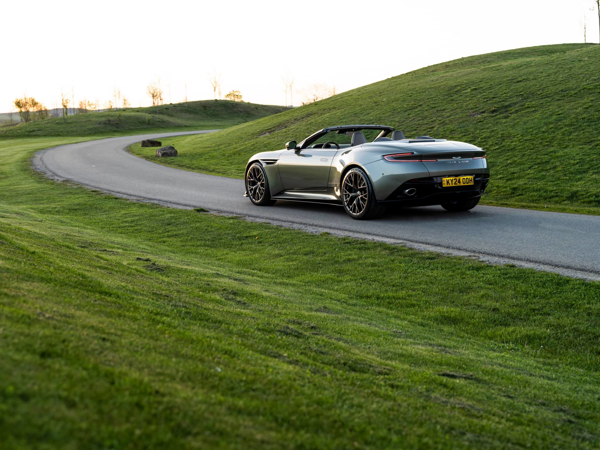 Vista dinámica del Aston Martin DB12 Volante en pleno asfalto, resaltando su diseño y elegancia.