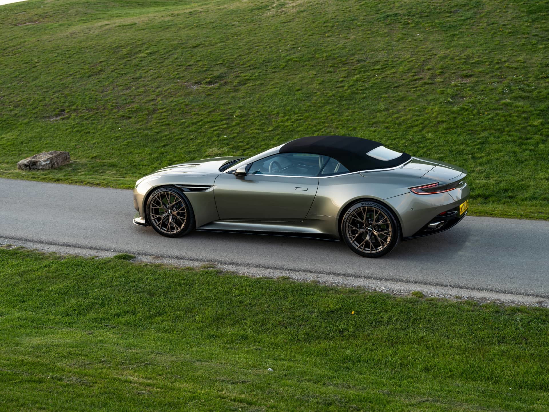 Vista lateral y trasera del Aston Martin DB12 Volante en movimiento.