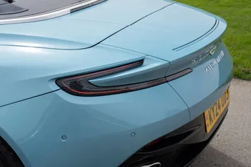 Vista trasera parcial del Aston Martin DB12 Volante, mostrando líneas y ópticas.