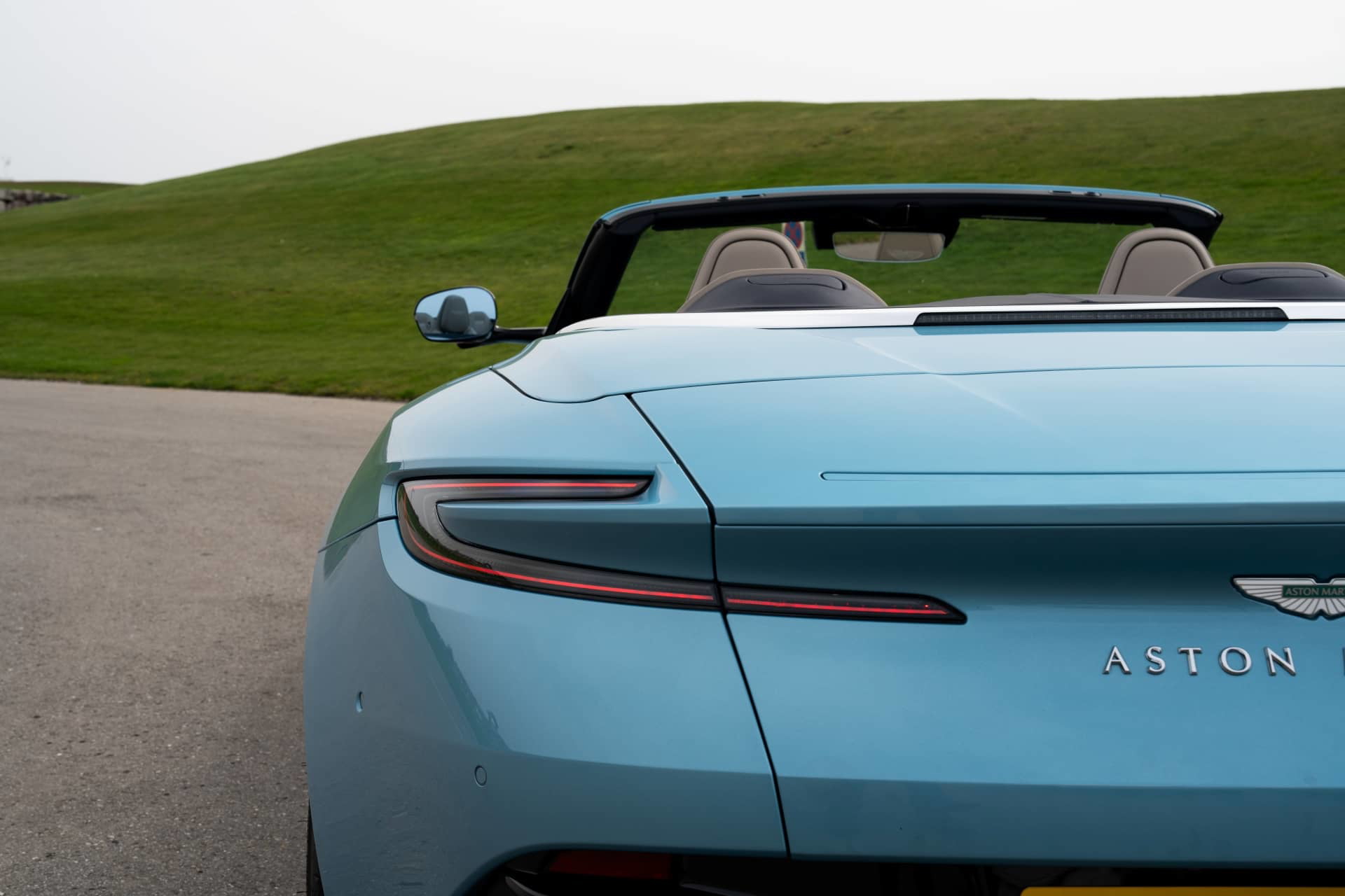 Vista lateral trasera del Aston Martin DB12 Volante con capota abierta.