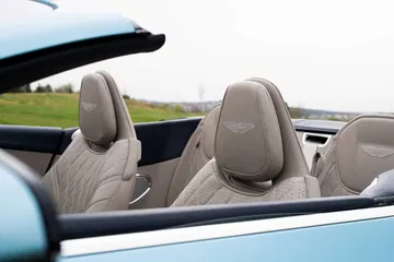 Vista detallada de los asientos de piel perforada con emblema de Aston Martin.