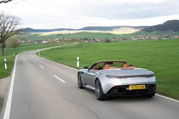Vista dinámica del Aston Martin DB12 Volante en carretera, enfatizando su elegante silueta.