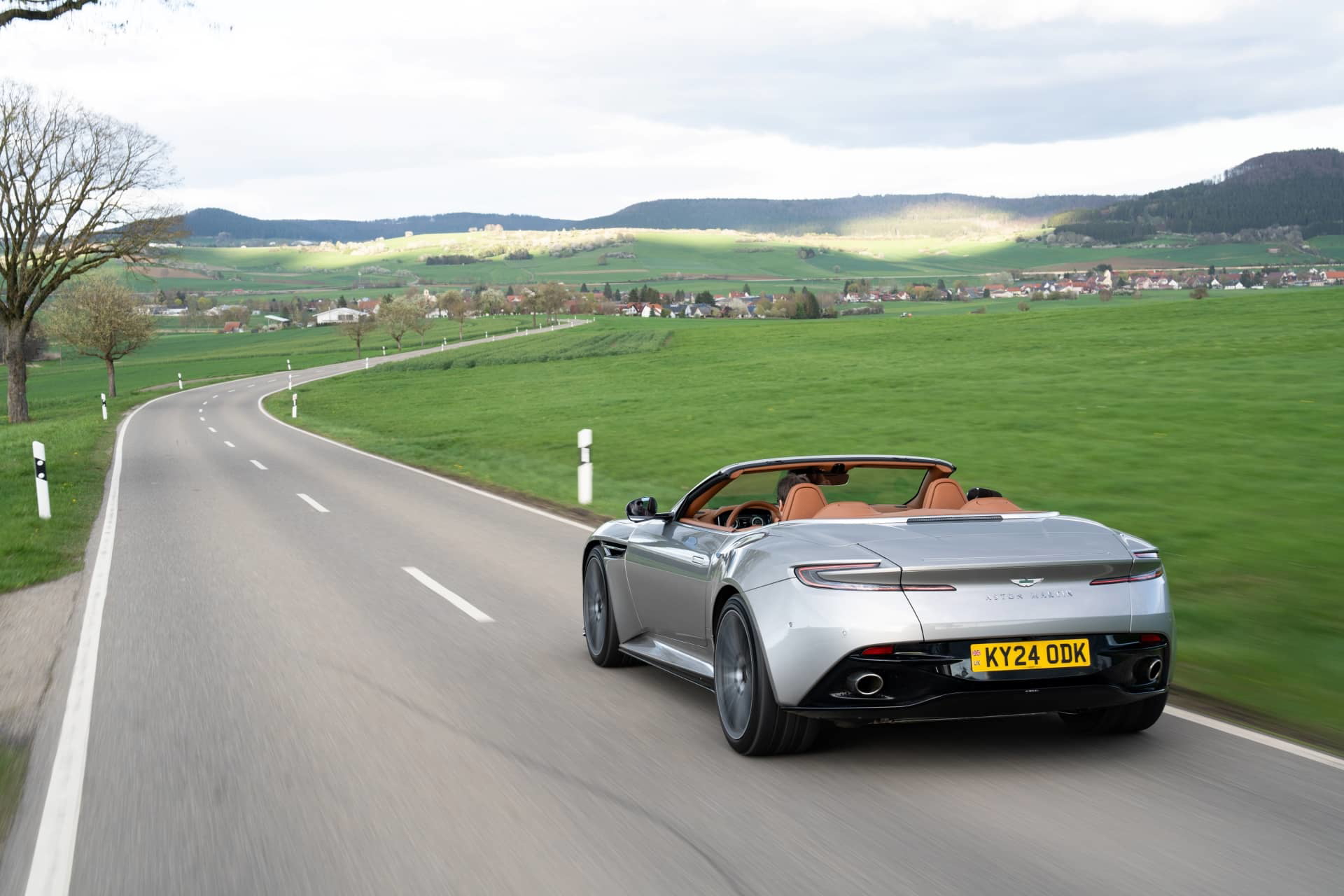 Vista dinámica del Aston Martin DB12 Volante en carretera, enfatizando su elegante silueta.