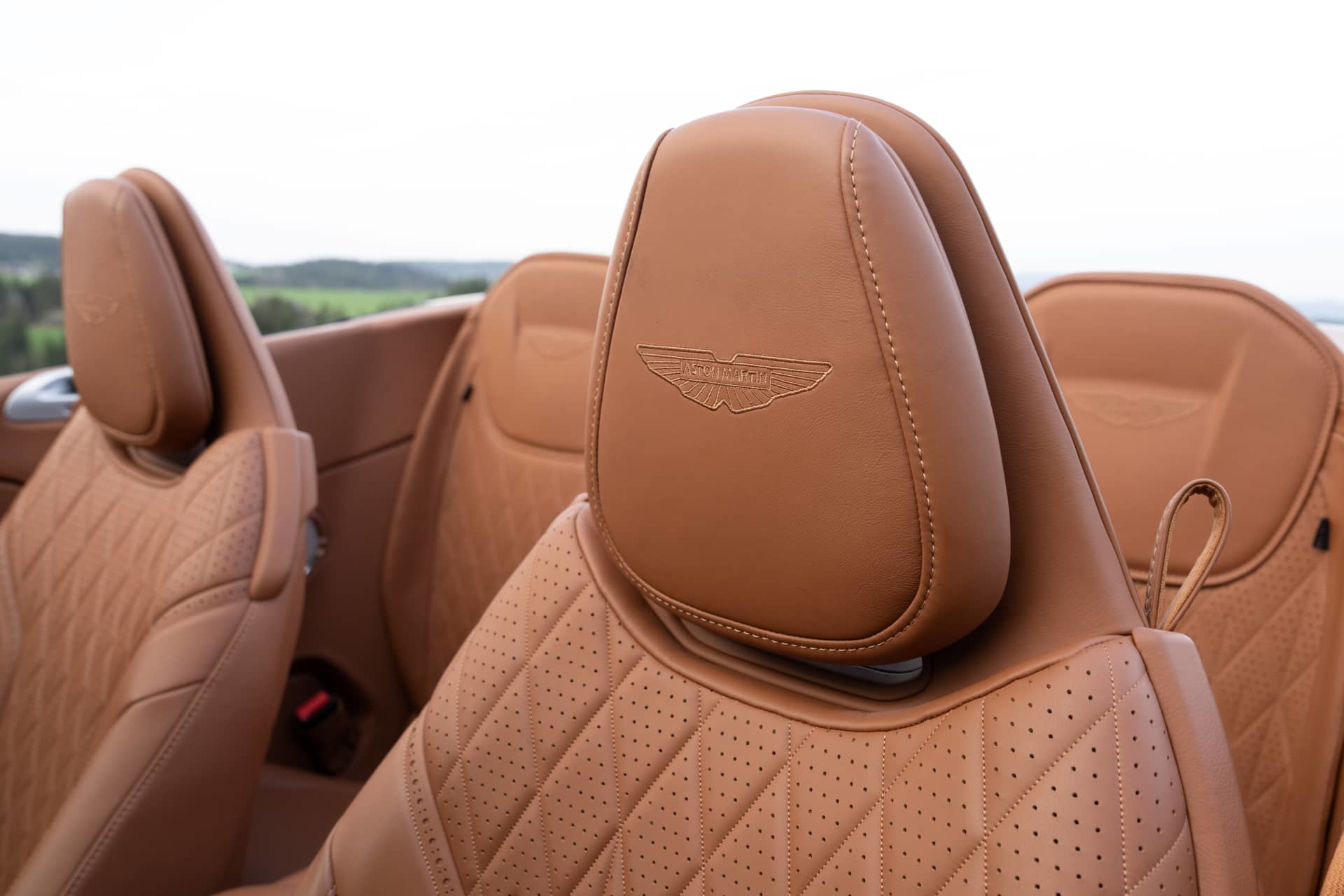 Vista detallada de los asientos de cuero con emblemático emblema Aston Martin.