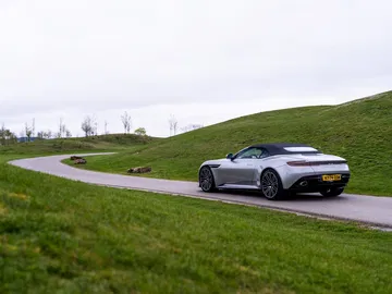 Vista lateral y trasera del Aston Martin DB12 Volante 2024 en movimiento.