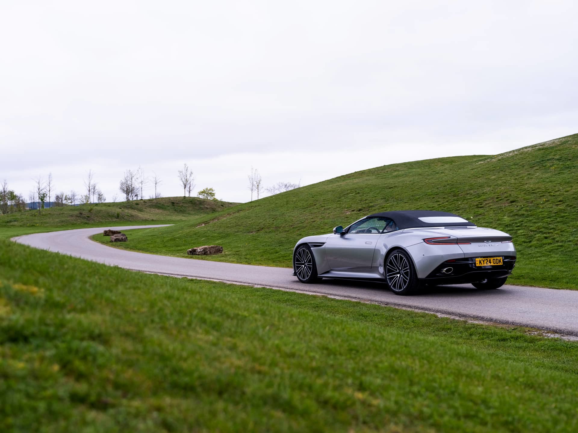 Vista lateral y trasera del Aston Martin DB12 Volante 2024 en movimiento.