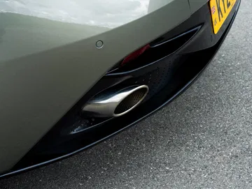 Detalle de la salida de escape de un Aston Martin DB12 Volante, simbolizando potencia y diseño.