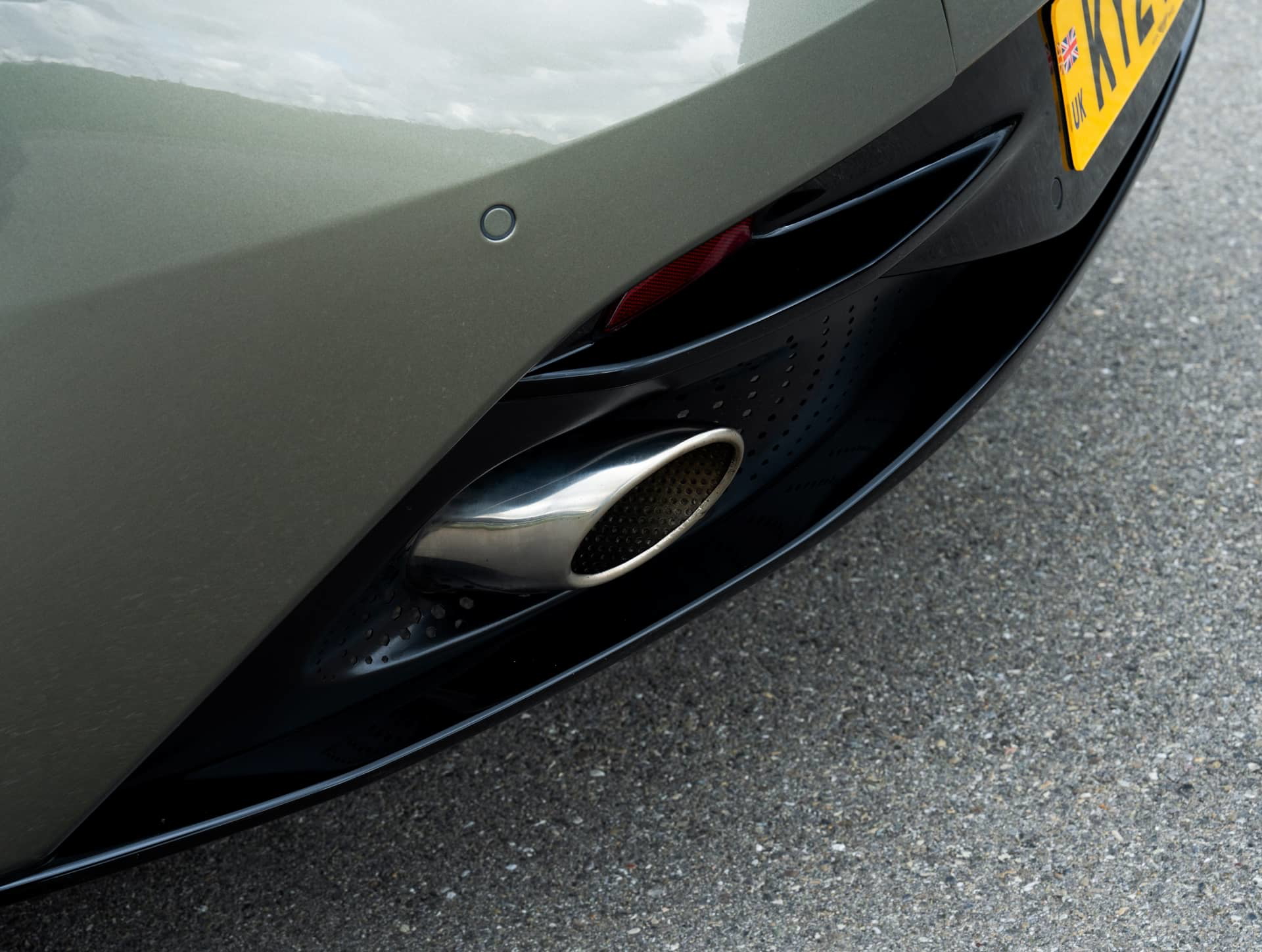 Detalle de la salida de escape de un Aston Martin DB12 Volante, simbolizando potencia y diseño.