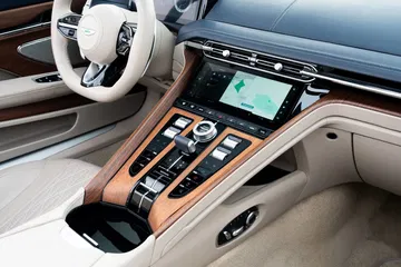 Vista de la consola central del Aston Martin DB12 Volante con acabados en madera y detalles metálicos.