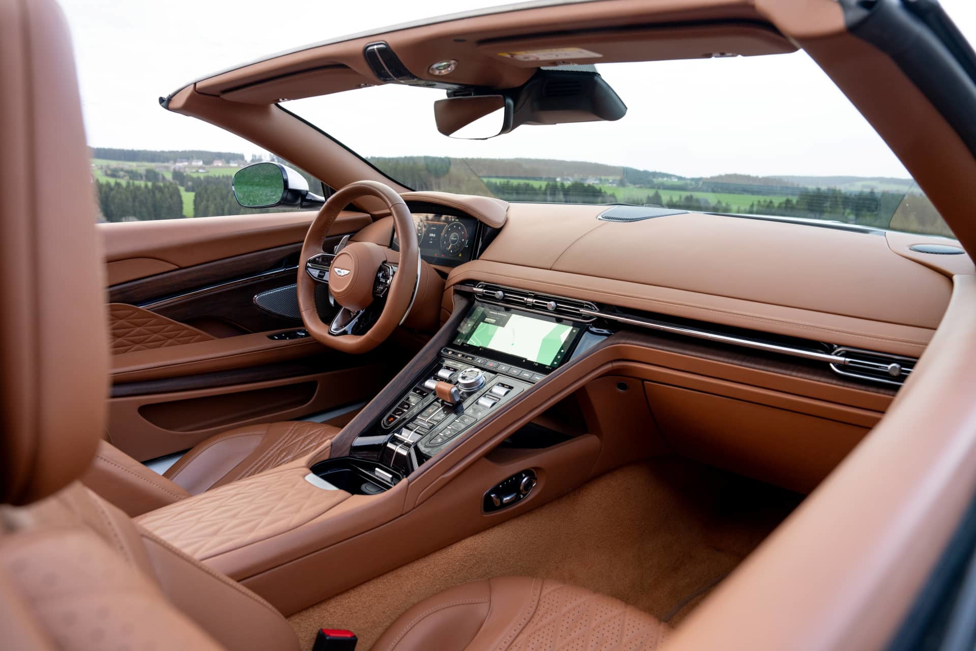 Vista lateral interna del Aston Martin DB12 Volante, mostrando su lujosa cabina y asientos de cuero.