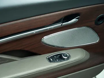 Vista del detallado acabado de la puerta con inserciones de madera y sistema de audio premium.