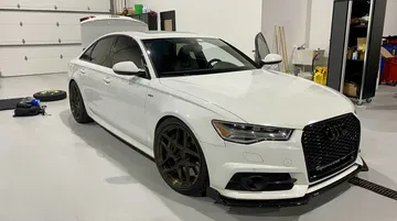 Vista lateral y delantera de un Audi RS6 en un taller, enfatizando su diseño deportivo y agresivo.