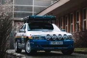 Vista frontal y lateral de un BMW Serie 7 preparado para rally, con barras de luces y portaequipajes.